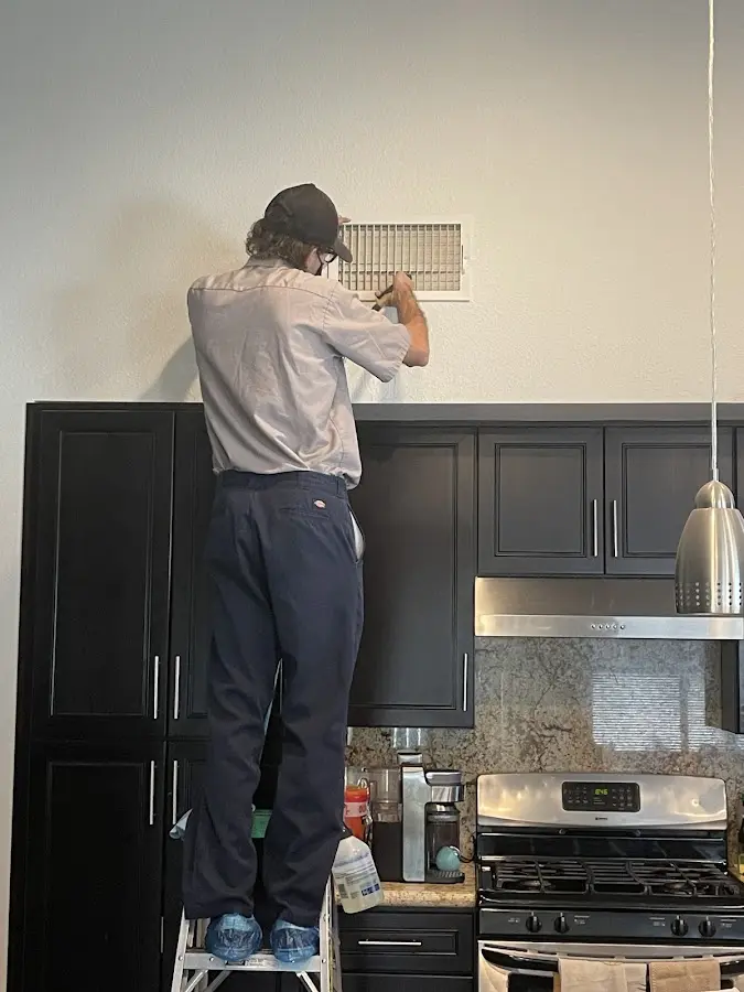 Technician inspecting an air vent during HVAC service in Richmond Heights